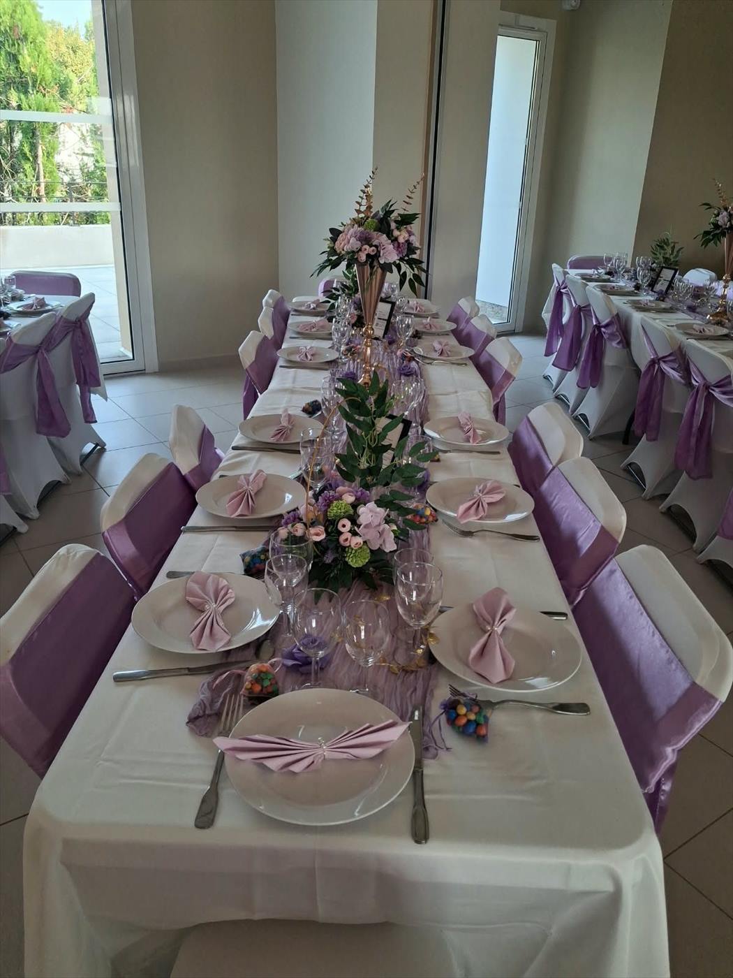 Table de réception dressée en rose et blanc, couverts et bouquets