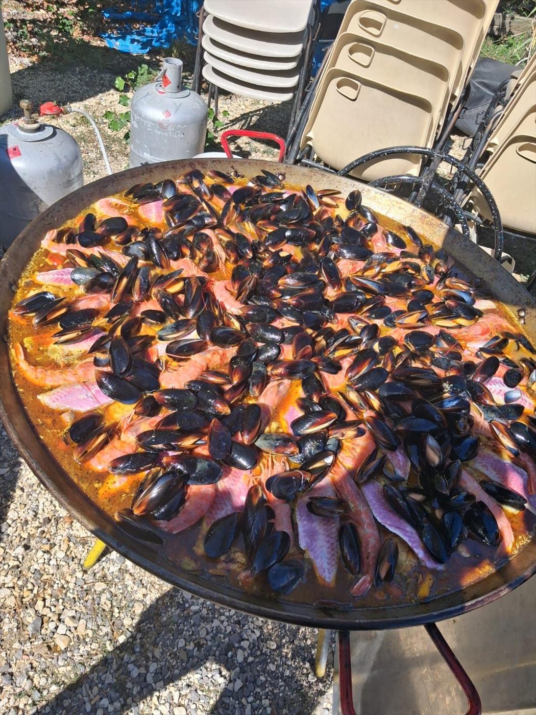 Paella au saumon et aux moules servie en extérieur