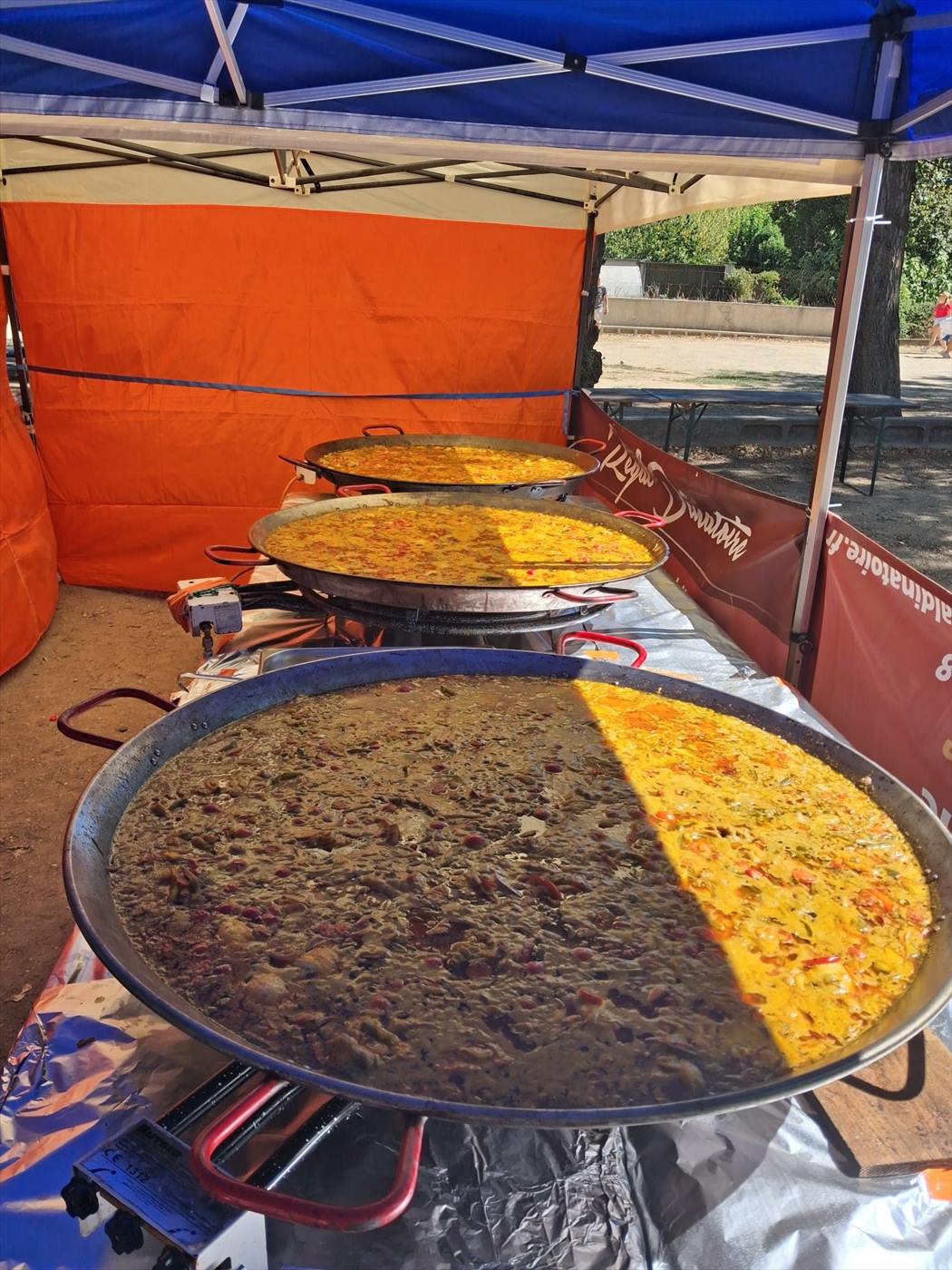 Deux paellas géantes préparées sous barnum pour une fête votive