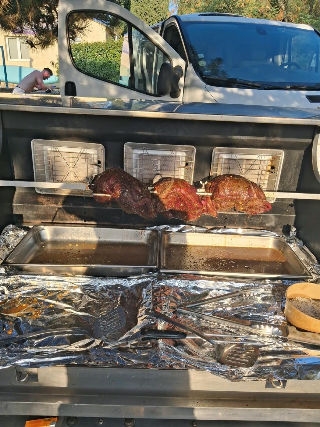 Broche installée à l'arrière du camion traiteur, viandes en cours de cuisson