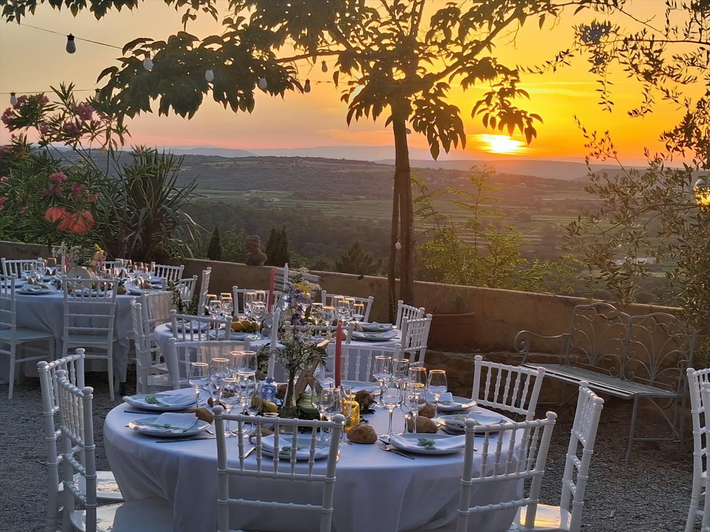 Tables rondes dressées face au coucher de soleil pour un mariage dans le Gard