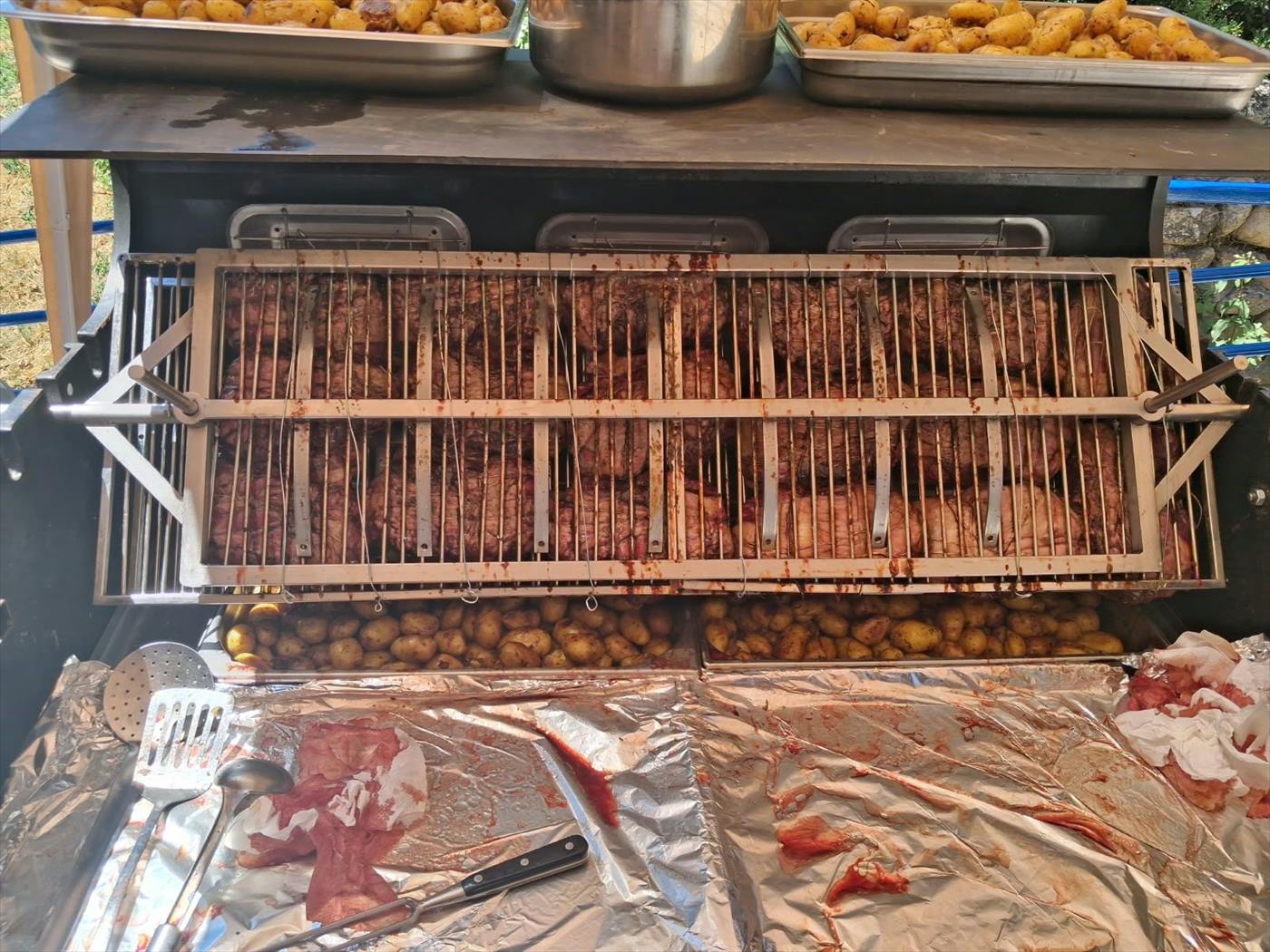 Brochettes et travers de porc alignés sur la broche au-dessus des braises